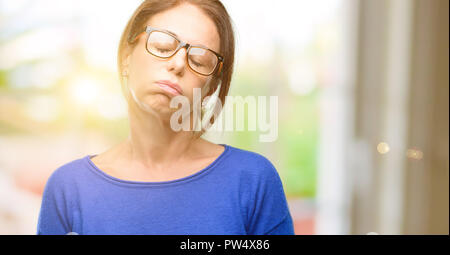 Middle age woman wearing wool sweater and glasses with sleepy expression, being overworked and tired Stock Photo