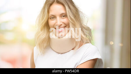 Young injured woman wearing neck brace holding something in empty hand Stock Photo