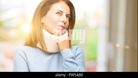 Injured woman wearing neck brace collar thinking and looking up expressing doubt and wonder Stock Photo