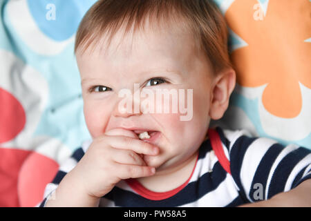 One year old Alexander James eats a banana wafer in a high chair Stock Photo