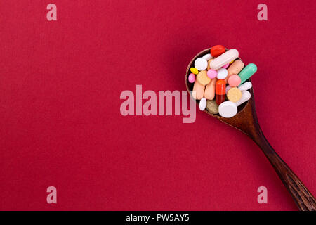 Different colorful pills and capsules in wooden spoon. Global pharmaceutical industry for billions dollars per year. Pharmaceutical drugs for use as m Stock Photo