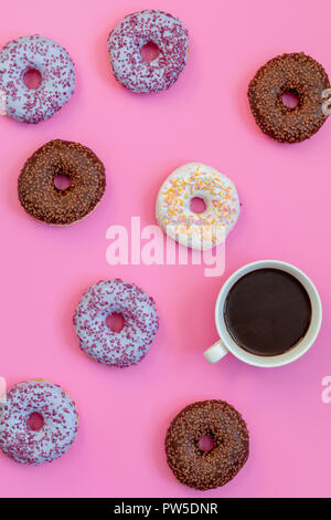 Delicious glazed donuts and cup of coffee on pink surface. Flat lay minimalist food art background. Top view. Stock Photo