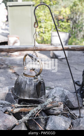 Metal camp kettle hanging over the coals campfire Stock Photo