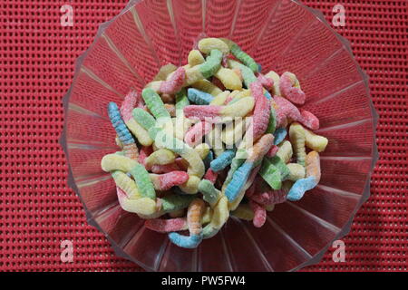Close-up of gummy worm candy in plastic bowl on an orange table Stock Photo
