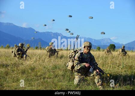 U.S. Army Paratroopers assigned to the Brigade Support Battalion, 173rd Airborne Brigade, provide security after an airborne operation from a U.S. Air Force 86th Air Wing C-130 Hercules aircraft at Juliet Drop Zone in Pordenone, Italy Sept. 21, 2017. The 173rd Airborne Brigade is the U.S. Army Contingency Response Force in Europe, capable of projecting ready forces anywhere in the U.S. European, Africa or Central Commands' areas of responsibility. Stock Photo