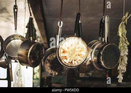 Pots and pans hanging on hooks in a farm kitchen. Stock Photo