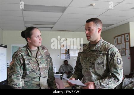 Staff Sgt. Cole Champion (right), a motor transport operator assigned to the 1176th Transportation Company of the Tennessee National Guard, assigned to the 101st Airborne Division Sustainment Brigade, 101st Abn. Div., speaks to Staff Sgt. Lisa Evans, assigned to the 541st Transportation Company, 129th Combat Sustainment Support Battalion, 101st Abn. Div. Sust. Bde, about upcoming missions in the company on Fort Campbell, Kentucky. Champion, who integrated to the battalion as part of the Army's Associated Unit Pilot Program, recently earned his air assault badge. Stock Photo