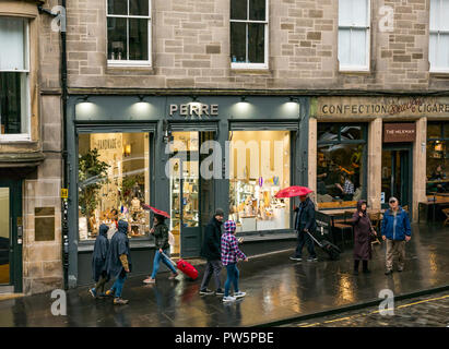 Edinburgh, Scotland, United Kingdom, 12th October 2018. UK Weather: Rain heralds the arrival of Storm Callum in the capital city, but doesn't deter the tourists. People holding umbrellas walk past the shop windows on Cockburn Street in the rain Stock Photo