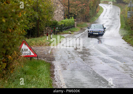 Flintshire, North Wales, 13th October 2018. UK Weather: Heavy rain for most today with weather warnings in place and flood warnings for parts of Wales. A car travelling through flood waters along a rural road near to the village of Lixwm, Flintshire  © DGDImages/AlamyNews Stock Photo