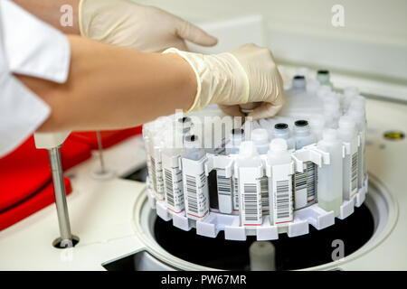 Laboratory assistant places labeled samples in a centrifuge, side view, close-up Stock Photo