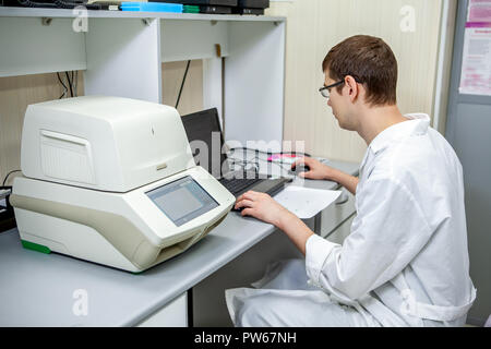 laboratory specialist examines the data obtained on a special apparatus for analyzing samples on a computer Stock Photo