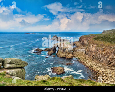Rocky coastline of Lands End, Cornwall, UK, with the arch, Enys Dodnan, and the rock formation The Armed Knight, with the Longships Lighthouse offshor Stock Photo