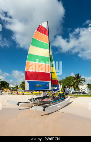 Bridgetown, Barbados - December 18, 2016: Brownes beach at ocean coast with people and colorful sail on a Catamaran at sunny day in Carlisle bay, Brid Stock Photo