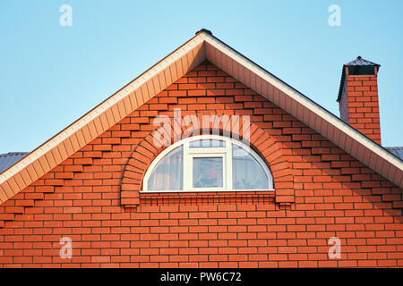 A small window under the roof in a brick cottage Stock Photo