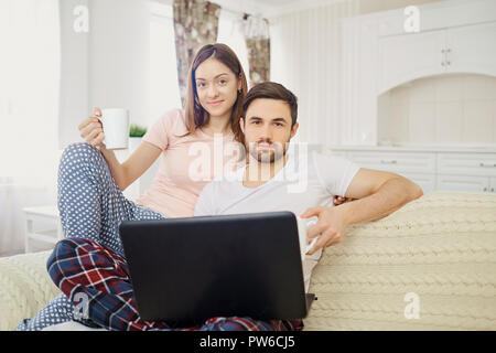 Husband and wife sitting with a laptop read at home. Stock Photo