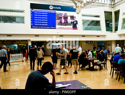 passengers looking up at departure board,standing,sitting,waiting for information about delayed trains at the euro tunnel terminal England,UK. Stock Photo