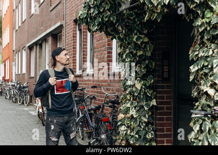 A tourist goes to the guesthouse or hostel in order to stay in a room that he booked or a student with a backpack returns home after his studies at the institute or on vacation. Stock Photo