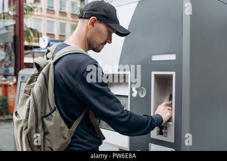 Tourist buys tickets for land or underground transport in Germany. Independent purchase of tickets for the tram, bus and train in a modern street machine. Stock Photo