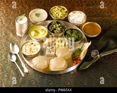 A FULL TRADITIONAL GUJARATI MEAL/ GUJARATI THALI: SHRIKHAND, RASMALAI,UNDHIYUN,TURIYA-PATRA VEGETABLE,KHAMAN DHOKLA, WHITE DHOKLA,GHOOGHARA,PURI, PAPA Stock Photo