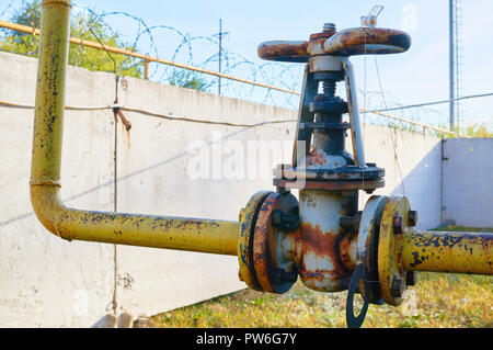 Older rusty valve on the gas pipe rusty yellow colored paint. Stock Photo