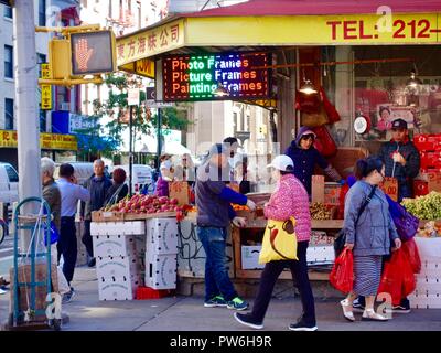 Asian shoppers outside vegetable, fruit market on corner of Mott Street in Chinatown, New York, NY, USA. Stock Photo