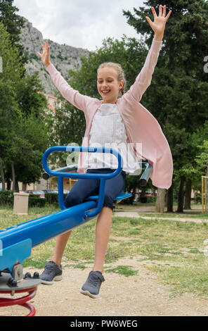 Smiling little girl on swing in the park Stock Photo