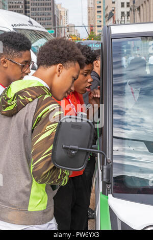 Detroit, Michigan - Students examine a self-driving van on display at the Detroit Moves Mobility Festival. The van, made by May Mobility, is being use Stock Photo