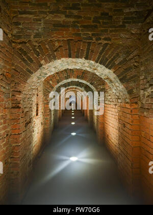 Dark brick long mystical arched corridor illuminated in the floor. Catacombs of Peter-Pavel's Fortress in St. Petersburg Stock Photo