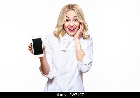 Gorgeous excited woman showing blank screen mobile phone over white background, celebrating victory and success. Very excited, cheering emotion. Stock Photo