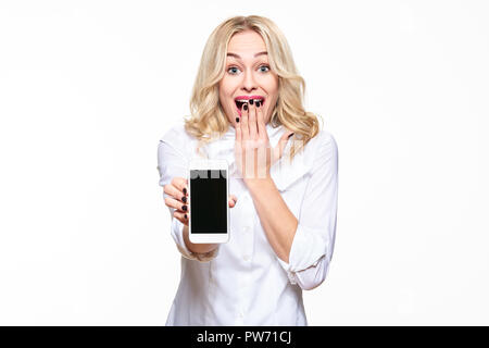 Gorgeous excited woman showing blank screen mobile phone over white background, celebrating victory and success. Very excited, cheering emotion. Stock Photo