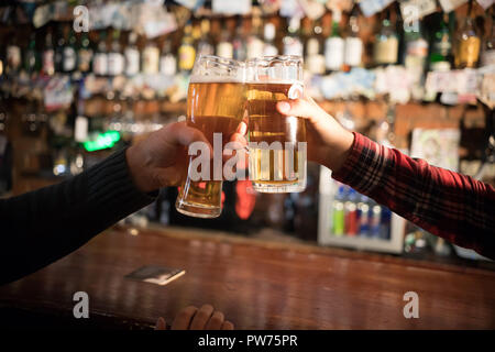 Cheers. Close-up of two men toasting with beer at the bar counter Stock Photo