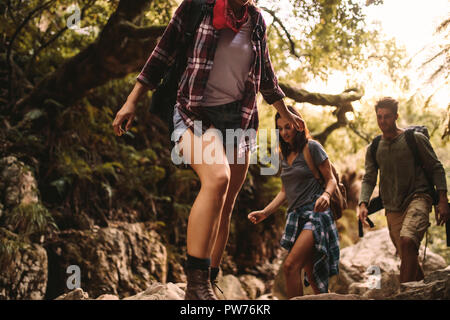 Two women and a man trekking a rough terrain. Friends trekking through a rocky trail in mountain. Stock Photo