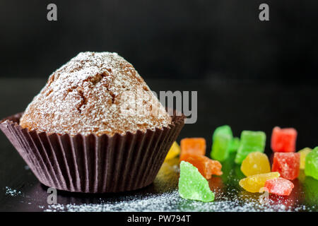 Freshly baked muffins with candied fruit on a black table Stock Photo