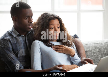 Black couple watching horror movie sitting on couch  Stock Photo
