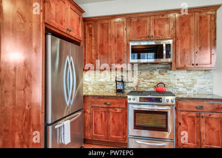 Wooden kitchen room with stone backsplash, granite countertops and stainless steel appliances. Northwest, USA Stock Photo