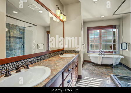 Master bathroom with double sink vanity cabinet, walk in shower and a freestanding clawfoot tub. Northwest, USA Stock Photo