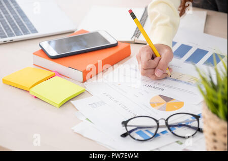 close up woman writing on business paper work report on office desk with mobile and laptop Stock Photo