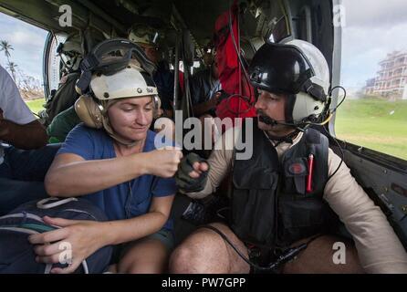 DOMINICA (Sept. 24, 2017) Naval Aircrewman (Helicopter) 2nd Class Andy Blessing 'fist bumps' an evacuee on an MH-60S Sea Hawk helicopter from Helicopter Sea Combat Squadron 22 (HSC-22), attached to the amphibious assault ship USS Wasp (LHD 1), during humanitarian aid operations on the  island of Dominica following the landfall of Hurricane Maria. The Department of Defense is supporting United States Agency for International Development (USAID), the lead federal agency, in helping those affected by Hurricane Maria to minimize suffering and is one component of the overall whole-of-government res Stock Photo