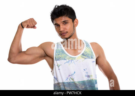 Studio shot of young handsome Indian man flexing his arm Stock Photo