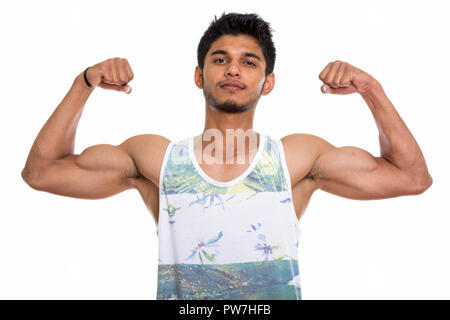 Studio shot of young handsome Indian man flexing both arms Stock Photo