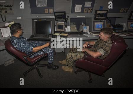Air Traffic Controller First Class Samuel Zacarias with Marine Corps Air Station (MCAS) Kaneohe Bay, and Pfc. Tommy Gilliard, an air traffic controller trainee with MCAS Kaneohe Bay, conduct radar training at the air traffic control tower, MCAS Kaneohe Bay, Sept. 20, 2017. Air traffic controllers work to safely organize and regulate the flow of air traffic, and prevent collisions between aircraft. Stock Photo