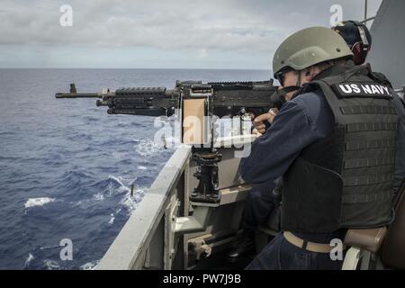 WESTERN PACIFIC (Sept. 22, 2017) Ens. Robert Paul, assigned to the Arleigh Burke-class guided-missile destroyer USS Chafee (DDG 90), and from Norfolk, Va., practices firing a M240B machine gun from Chafee’s bridge wing. Chafee is part of the U.S. 3rd Fleet and U.S. Naval Surface Forces, currently deployed to the U.S. 7th Fleet area of responsibility on a routine scheduled deployment. The forces of both fleets complement one another across the spectrum of military operations in the Pacific. Stock Photo