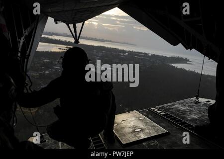 SAN JUAN, Puerto Rico (Sept. 24, 2017) Lance Cpl. Matthew Johnson, assigned to the 26th Marine Expeditionary Unit, looks out of the back of a CH-53E Superstallion as it flies over Puerto Rico. Kearsarge and the 26th MEU are assisting with relief efforts in the aftermath of Hurricane Maria. The Department of Defense is supporting the Federal Emergency Management Agency, the lead federal agency, in helping those affected by Hurricane Maria to minimize suffering and is one component of the overall whole-of-government response effort. Stock Photo