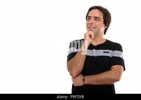 Studio shot of young happy Persian man smiling and thinking whil Stock Photo