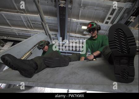 ARABIAN GULF (Sept. 24, 2017) Marine Lance Cpl. James Frank, from Marion, Ind., left, and Marine Lance Cpl. Kyle Verbeae, from Port Huron, Mich., wipe down flat panels on an F/A-18C Hornet assigned to the “Death Rattlers” of Marine Strike Fighter Squadron (VMFA) 323 in the hangar bay of the aircraft carrier USS Nimitz (CVN 68). Nimitz is currently deployed in the U.S. 5th Fleet area of operations in support of Operation Inherent Resolve. While in the region, the ship and strike group are conducting maritime security operations to reassure allies and partners, preserve freedom of navigation, an Stock Photo