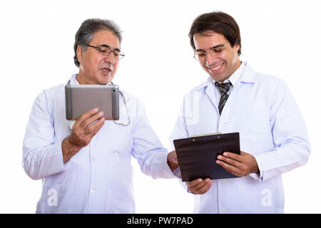 Studio shot of happy young and senior Persian man doctor smiling Stock Photo