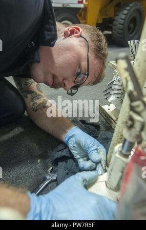 5TH FLEET AREA OF OPERATIONS (Sept. 27, 2017) Aviation Support Equipment Technician 3rd Class Austin Moshier, a native of Amarillo, Texas, assigned to the aircraft intermediate maintenance department aboard the amphibious assault ship USS America (LHA 6), adjusts a hydraulic lift in the hangar bay. America is the flagship for the America Amphibious Ready Group and, with the embarked 15th Marine Expeditionary Unit, is deployed to the U.S. 5th Fleet area of operations in support of maritime security operations to reassure allies and partners and preserve the freedom of navigation and the free fl Stock Photo