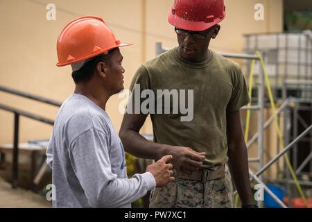 U.S. Marine Jeffrey Decen speaks with a Philippine Navy seabee during KAMANDAG construction operations at Esperanza Elementary School in Casiguran, Aurora, Philippines, Sept. 28, 2017. KAMANDAG is an acronym for the Filipino phrase “Kaagapay Ng Mga Mandirigma Ng Dagat,” which translates to “Cooperation of Warriors of the Sea,” highlighting the partnership between the Philippine and United States militaries. Decen is a fire team leader with Bravo Company, 9th Engineering Support Battalion, 3rd Marine Logistics Group, and is a native of Newark, New Jersey. Stock Photo