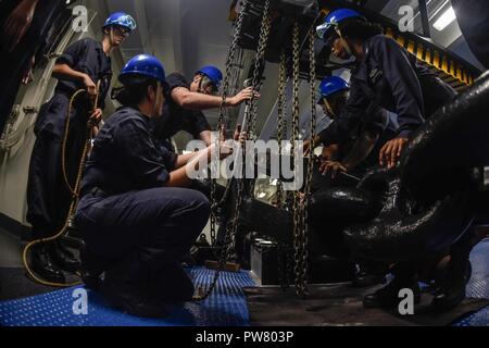 HONG KONG HARBOR (Oct. 2, 2017) – Deck department Sailors secure the starboard anchor in the forecastle of the Navy's forward-deployed aircraft carrier, USS Ronald Reagan (CVN 76), as the ship anchors off the coast of China prior to a scheduled port visit in Hong Kong. The port visit comes after routine operations in the South China Sea. Ronald Reagan, the flagship of Carrier Strike Group 5, provides a combat-ready force that protects and defends the collective maritime interests of its allies and partners in the Indo-Asia-Pacific region. Stock Photo