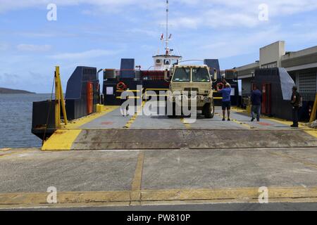 Spc. Joksan Toro, a motor transport operator assigned to Puerto Rico’s 755th National Guard Transportation Unit, maneuvers a military flatbed, loaded with Meals, Ready-To-Eat, onto a ferry headed to the Puerto Rico island Vieques, October 2, 2017. The top priority of the Department of Defense, working together to support Federal Emergency Management Agency, and local authorities in Puerto Rico is providing life-saving and life-sustaining support to those in the affected areas. Stock Photo